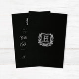 Elegant wedding invitation with black background, vintage-style white shield monogram surrounded by a laurel wreath, white calligraphy and serif fonts, ideal for formal or gothic weddings. - back side