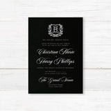 Elegant wedding invitation with black background, vintage-style white shield monogram surrounded by a laurel wreath, white calligraphy and serif fonts, ideal for formal or gothic weddings.