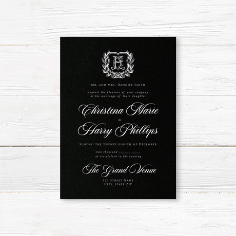 Elegant wedding invitation with black background, vintage-style white shield monogram surrounded by a laurel wreath, white calligraphy and serif fonts, ideal for formal or gothic weddings.