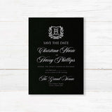 Save the Date card with black background, vintage-style shield crest encircled by a laurel wreath, and elegant white calligraphy and serif fonts for formal weddings.