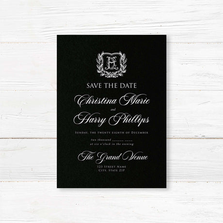 Save the Date card with black background, vintage-style shield crest encircled by a laurel wreath, and elegant white calligraphy and serif fonts for formal weddings.