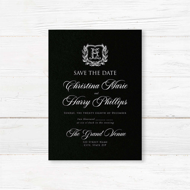 Save the Date card with black background, vintage-style shield crest encircled by a laurel wreath, and elegant white calligraphy and serif fonts for formal weddings.