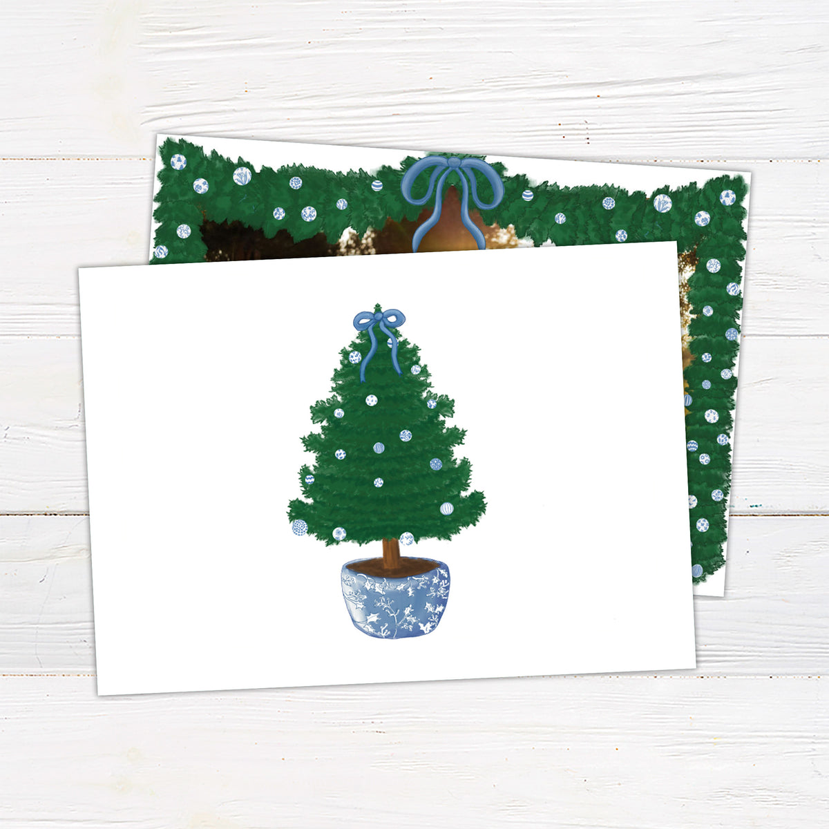 A personalized blue Christmas garland family holiday photo card framed with watercolor evergreen garland, blue and white ornaments, and a blue bow. The coordinating design features elegant blue script and a decorated Christmas tree with matching blue accents. - horizontal back view.