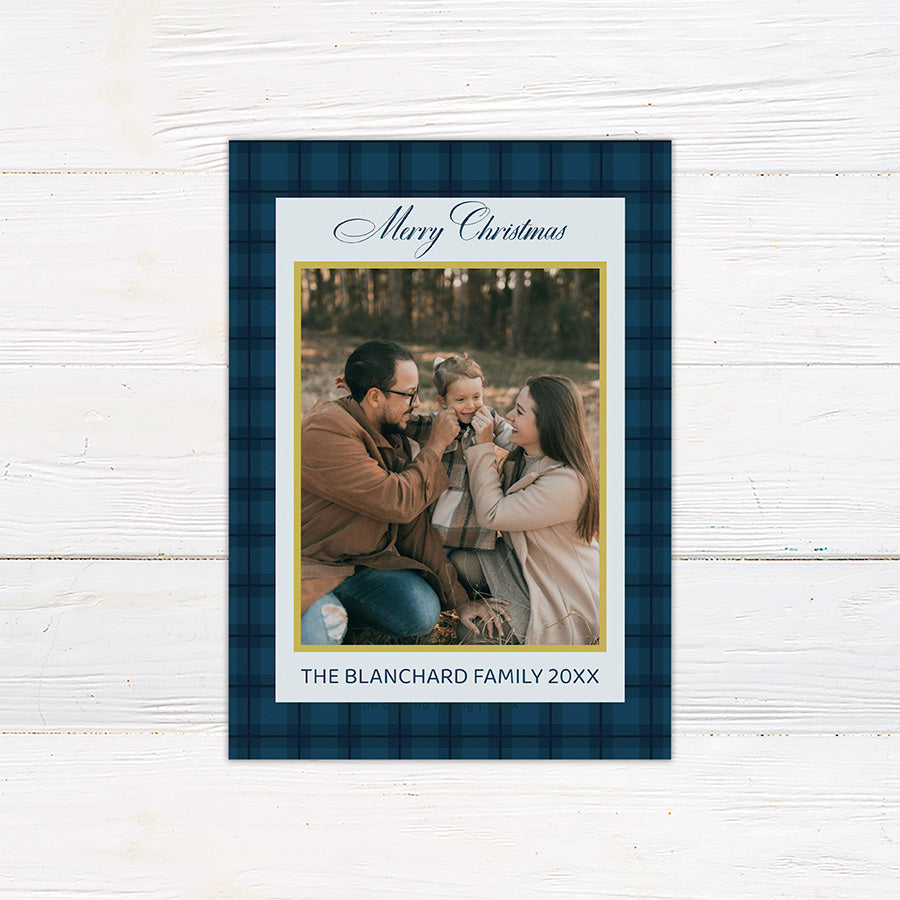 Blue plaid Christmas photo card featuring a family photograph with elegant script, gold accents, and personalized family text. The coordinating back features large gold JOY lettering with a faith-inspired Christmas message.