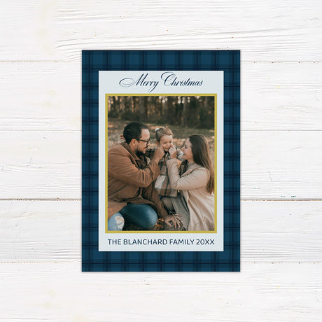 Blue plaid Christmas photo card featuring a family photograph with elegant script, gold accents, and personalized family text. The coordinating back features large gold JOY lettering with a faith-inspired Christmas message.