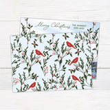 Personalized Christmas photo card featuring a family photo framed by festive greenery, holly, berries, and red cardinals. Back
