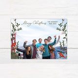 Personalized Christmas photo card featuring a family photo framed by festive greenery, holly, berries, and red cardinals.