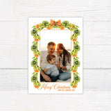 Personalized Christmas citrus garland family photo card featuring watercolor evergreen garlands, orange slices, and decorative orange bows surrounding a customizable family photograph. The coordinating back features a horizontal citrus greenery garland on a white background.