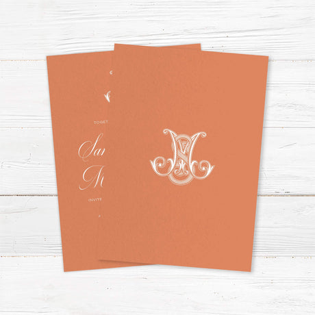 Terracotta wedding invitation with white calligraphy and ornate Celtic-style monogram - back side