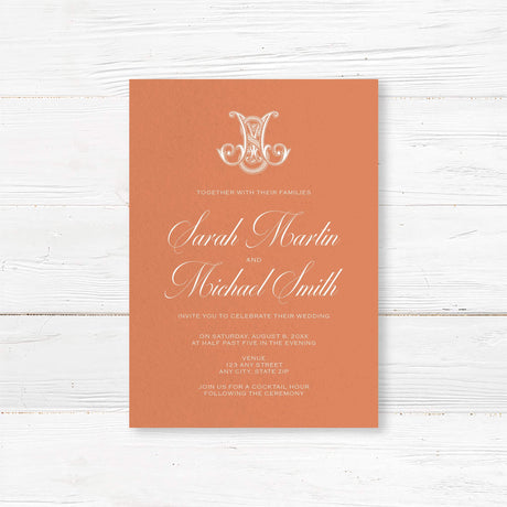 Terracotta wedding invitation with white calligraphy and ornate Celtic-style monogram