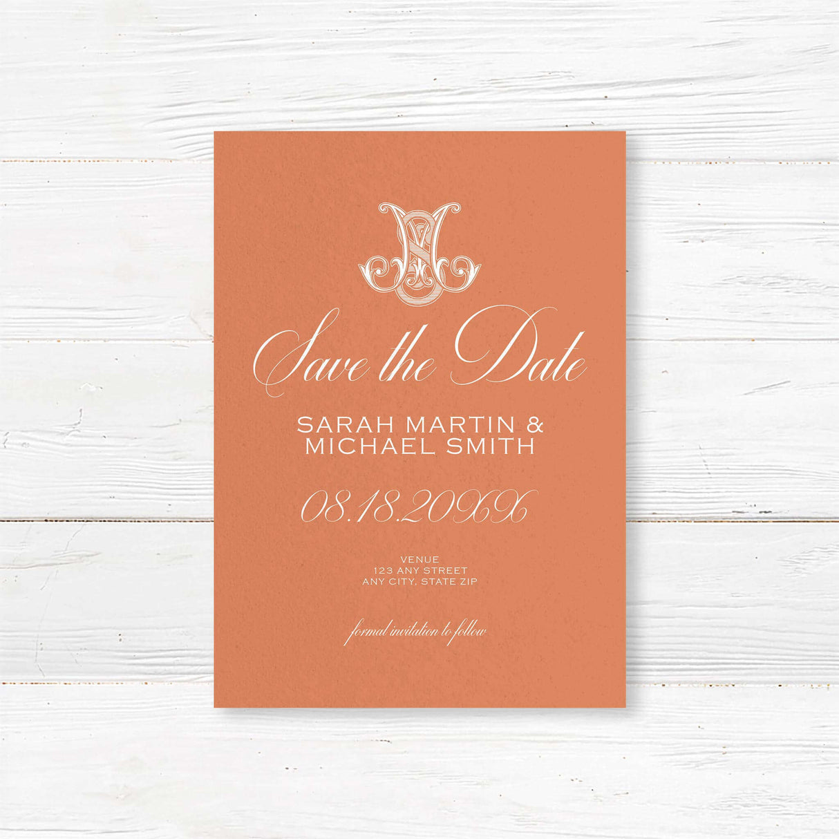 Terracotta save the date card with white script and ornate Celtic initial monogram