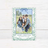 Personalized family Christmas photo card framed with delicate watercolor greenery and an elegant bow.