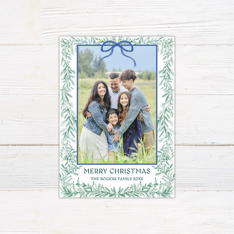 Personalized family Christmas photo card framed with delicate watercolor greenery and an elegant bow.