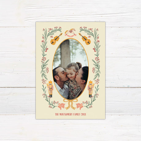 Personalized Christmas photo card featuring an oval family photo surrounded by nutcrackers, greenery, berries, bows, and musical instruments.