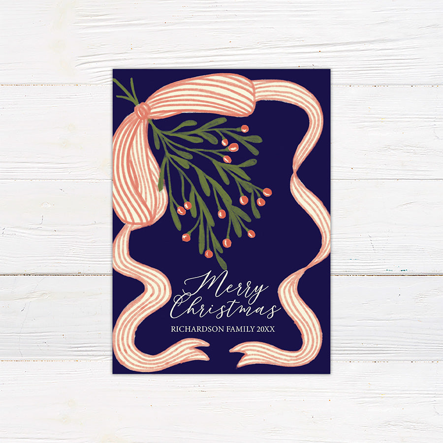 Personalized Christmas card featuring festive mistletoe, berries, striped ribbon, and a Merry Christmas greeting. The reverse features a four-photo family collage for sharing favorite memories.