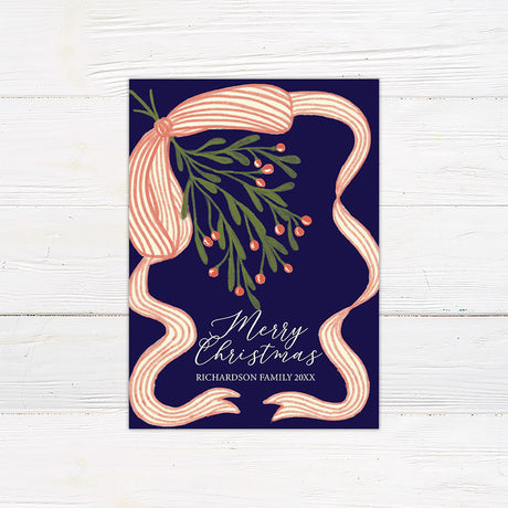 Personalized Christmas card featuring festive mistletoe, berries, striped ribbon, and a Merry Christmas greeting. The reverse features a four-photo family collage for sharing favorite memories.
