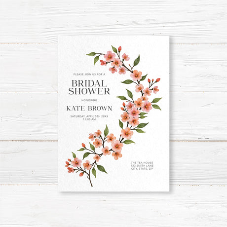 Bridal shower invitation featuring a watercolor cherry blossom vine with soft pink flowers and green leaves, printed on premium cardstock.