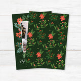 Personalized festive garland frame photo Christmas card featuring a family photograph framed by festive greenery, poinsettias, holly, and berries with elegant Merry Christmas lettering. The coordinating back features a repeating Christmas botanical pattern on a deep green background. - back.