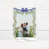 Personalized Christmas photo card featuring a family picture framed by cascading greenery, golden pears, and an elegant ribbon bow. The design includes a Merry Christmas greeting with a custom family name and year.