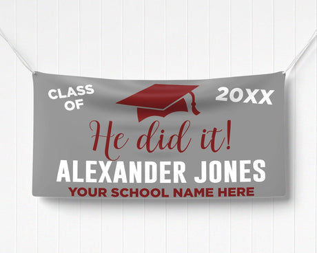 Bold "He Did It!" Graduation Vinyl Banner featuring a mortarboard cap, class year, and celebratory typography. Perfect for indoor and outdoor graduation decorations. Customizable colors and school name for any high school or college graduate. gray and red