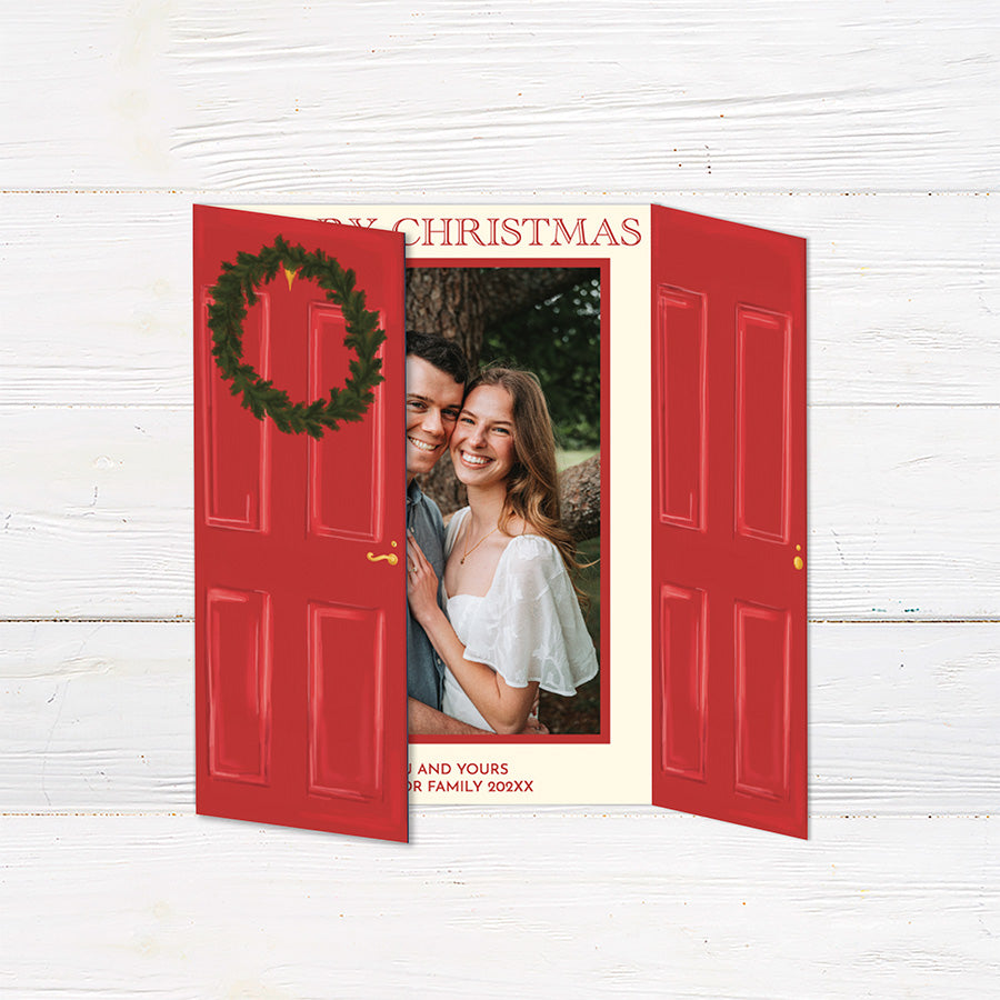 Personalized Home for the Holidays Christmas gatefold photo card featuring festive red double doors decorated with evergreen wreaths and customizable family photos. The folding holiday card opens to reveal a large photo and personalized Christmas greeting with an additional four-photo collage. Two-photo variant. 