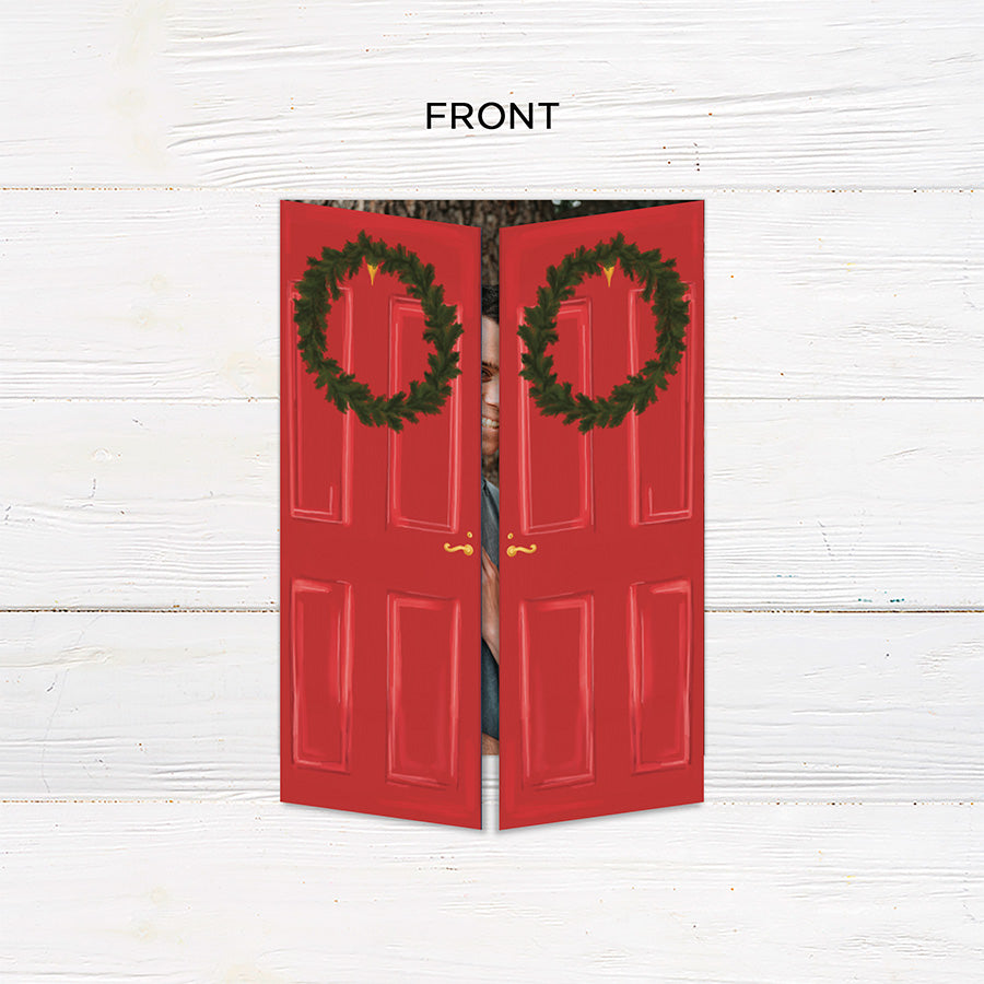 Personalized Home for the Holidays Christmas gatefold photo card featuring festive red double doors decorated with evergreen wreaths and customizable family photos. The folding holiday card opens to reveal a large photo and personalized Christmas greeting with an additional four-photo collage. Four-photo variant. - front.