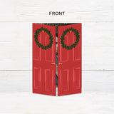 Personalized Home for the Holidays Christmas gatefold photo card featuring festive red double doors decorated with evergreen wreaths and customizable family photos. The folding holiday card opens to reveal a large photo and personalized Christmas greeting with an additional four-photo collage. Four-photo variant. - front.