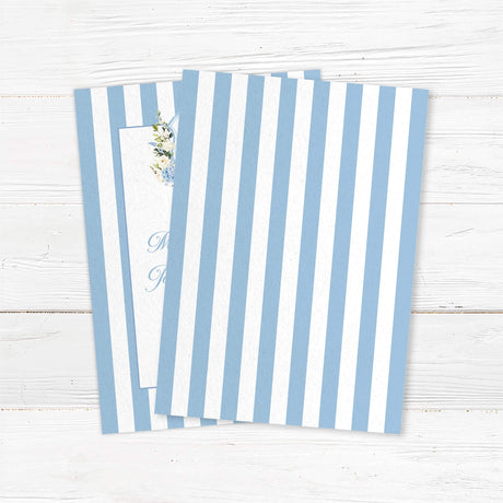 Wedding invitation with powder blue and white vertical stripes, floral monogram crest of blue hydrangeas and white roses, and elegant script and serif fonts on a white center panel, ideal for spring weddings. - back side