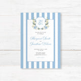 Wedding invitation with powder blue and white vertical stripes, floral monogram crest of blue hydrangeas and white roses, and elegant script and serif fonts on a white center panel, ideal for spring weddings.