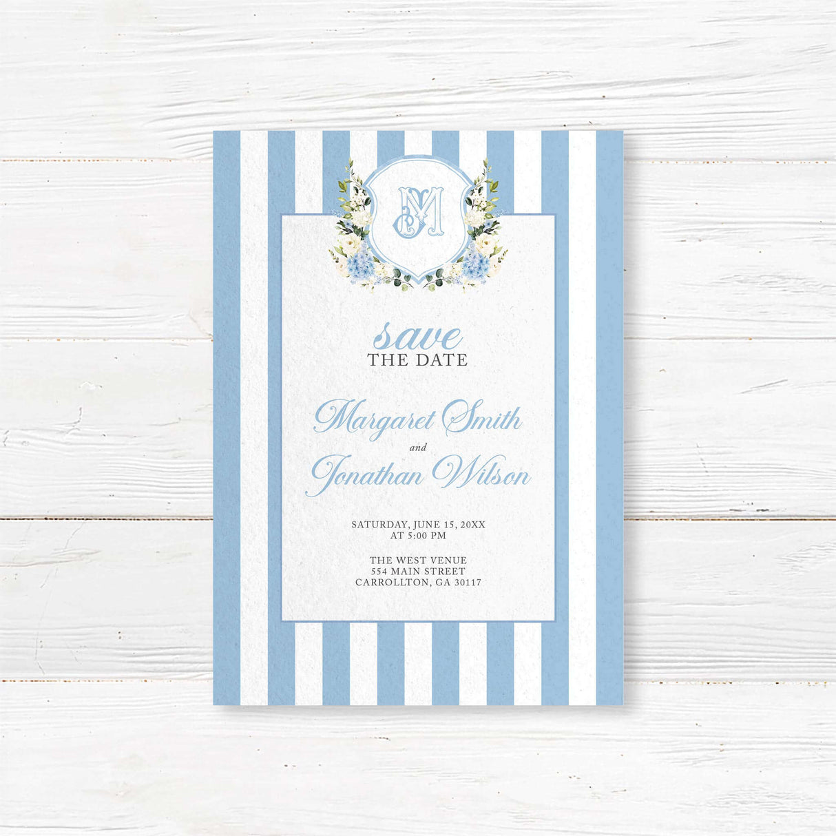 Save the Date card featuring powder blue and white vertical stripes, floral monogram crest with hydrangeas and roses, and elegant fonts, ideal for spring or garden weddings.