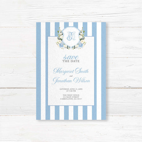 Save the Date card featuring powder blue and white vertical stripes, floral monogram crest with hydrangeas and roses, and elegant fonts, ideal for spring or garden weddings.