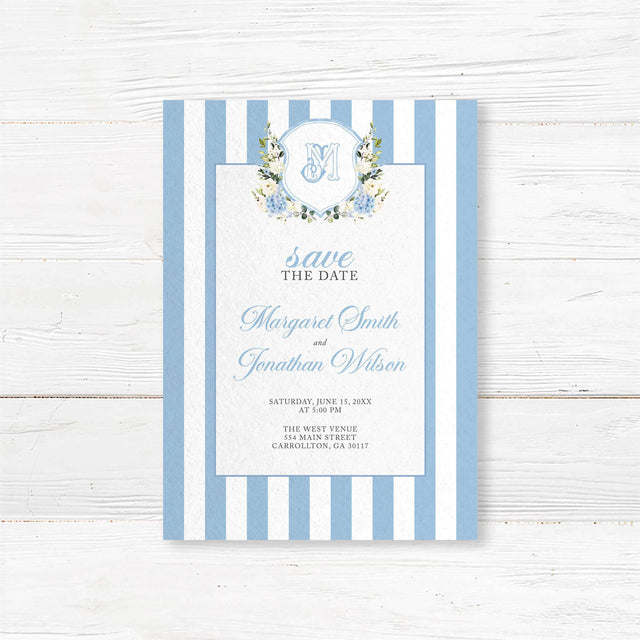 Save the Date card featuring powder blue and white vertical stripes, floral monogram crest with hydrangeas and roses, and elegant fonts, ideal for spring or garden weddings.