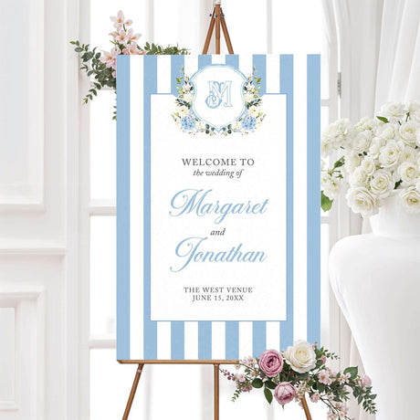 Wedding welcome sign featuring powder blue and white vertical stripes, floral crest with hydrangeas and white roses, and elegant fonts, ideal for classic spring wedding ceremonies.