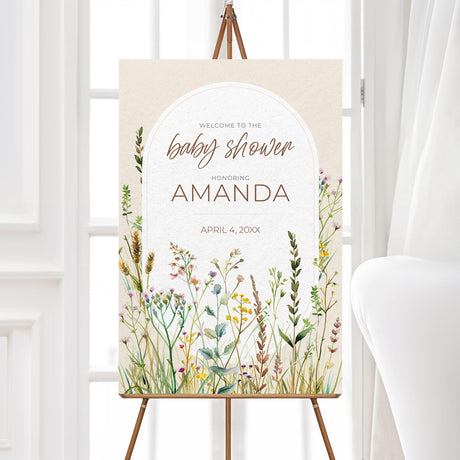 "A vertical welcome sign with a soft, neutral background featuring an elegant arched frame in the center. The text is in a mix of stylish script and serif fonts, warmly greeting guests to the baby shower. The bottom and sides of the design are adorned with delicate watercolor wildflowers in pastel shades of pink, yellow, green, and purple, creating a rustic and nature-inspired aesthetic. The overall look is soft, inviting, and beautifully themed for the event."
