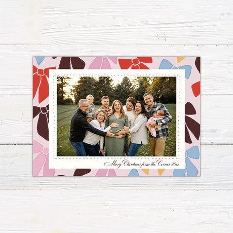 Personalized family Christmas photo card featuring a large photograph surrounded by a playful pattern of colorful ribbon bows. The coordinating back features an all-over illustrated bow pattern.