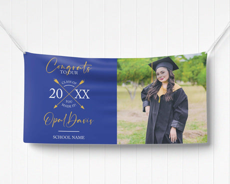 Graduation vinyl banner with split design featuring bold congratulatory text, crossed arrow class year emblem, and a custom graduate photo. Perfect for high school, college, or university graduation parties and ceremonies. Durable, weatherproof, and available in custom colors for a standout celebration. blue