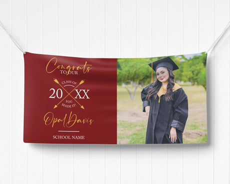 Graduation vinyl banner with split design featuring bold congratulatory text, crossed arrow class year emblem, and a custom graduate photo. Perfect for high school, college, or university graduation parties and ceremonies. Durable, weatherproof, and available in custom colors for a standout celebration. red and gold