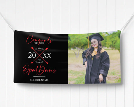 Graduation vinyl banner with split design featuring bold congratulatory text, crossed arrow class year emblem, and a custom graduate photo. Perfect for high school, college, or university graduation parties and ceremonies. Durable, weatherproof, and available in custom colors for a standout celebration. black and red