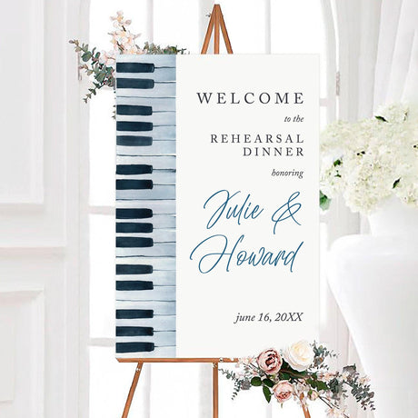 A stylish "Welcome" sign for a rehearsal dinner, featuring a piano key design along the left edge. The text reads "WELCOME to the REHEARSAL DINNER" in elegant, modern typography. The sign is displayed on an easel, with a soft, neutral background and subtle floral accents, creating a sophisticated and inviting atmosphere for a music-themed celebration.