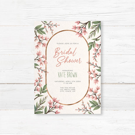 Elegant bridal shower invitation featuring soft pink blossoms, greenery, and a gold arch frame, printed on premium cardstock.