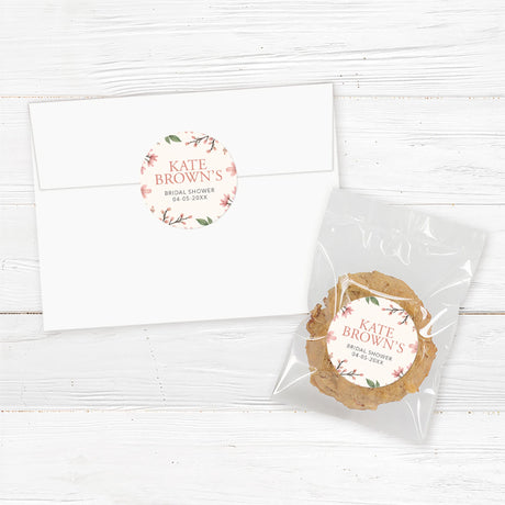 Round bridal shower sticker featuring soft pink blossoms, greenery, and a gold frame, perfect for favors, gifts, and envelope seals.