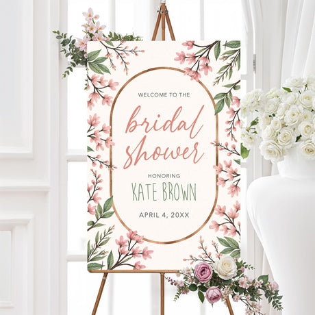 Bridal shower welcome sign featuring soft pink blossoms, greenery, and a gold frame, printed on high-quality material for elegant event décor.