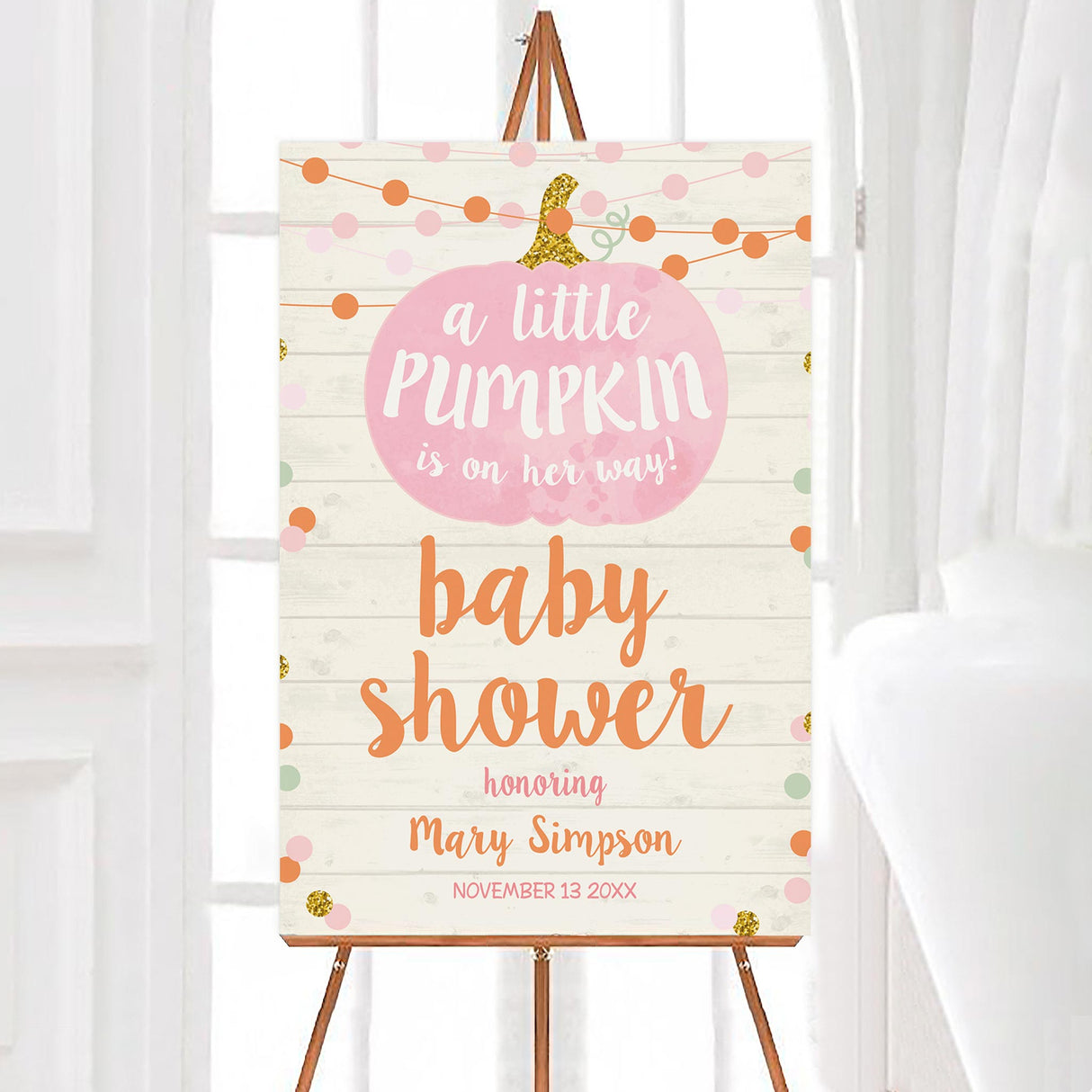 A pumpkin on the way baby shower welcome sign with a pink pumpkin and fall decorations. The design has a light wood background with pastel accents.