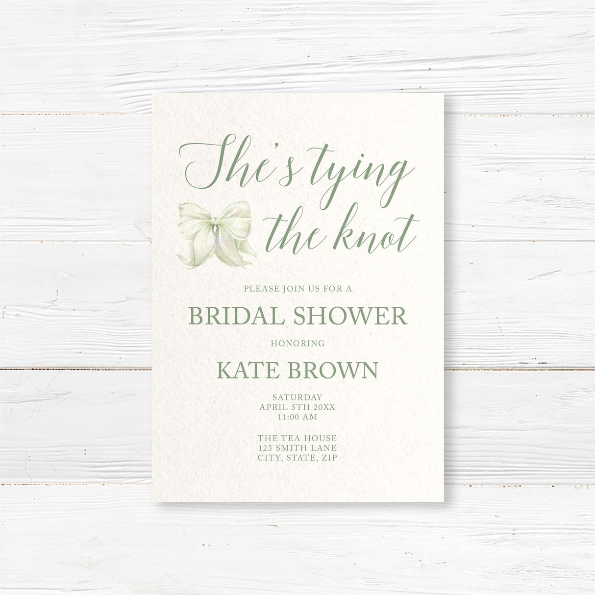 Watercolor bow bridal shower invitation that reads "She’s Tying the Knot" with floral accents,