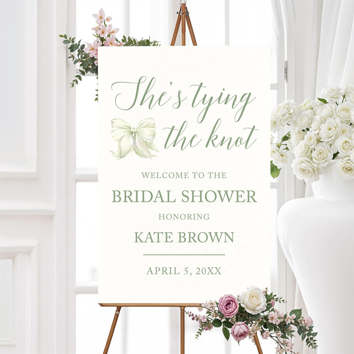Watercolor bow bridal shower welcome sign that reads "She’s Tying the Knot" with floral accents,