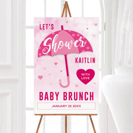 A shower with love pink baby shower welcome sign with an umbrella and heart accents. The design uses a soft watercolor background.