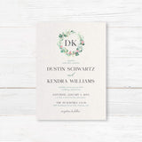 Wedding invitation with botanical wreath monogram, soft watercolor greenery, serif and script fonts on textured white paper