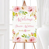 A floral spring blossoms baby shower welcome sign with pink flowers and greenery. The design includes soft watercolor details.