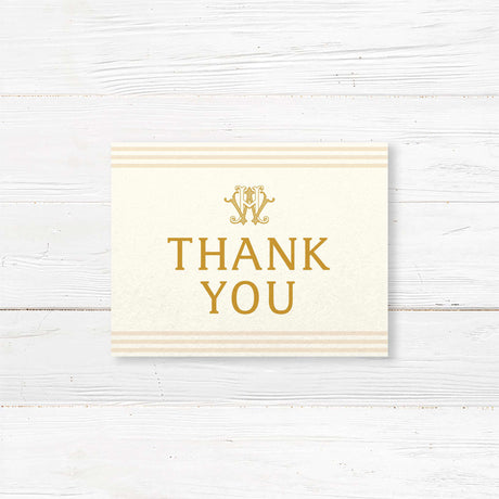 Wedding thank you card with elegant gold serif fonts, cream background, and neutral stripe accents, part of a monogrammed gold wedding stationery suite.