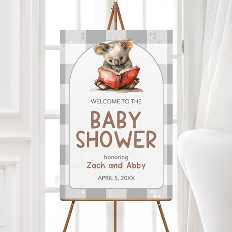 Welcome sign featuring a watercolor koala reading a red book, set against a neutral buffalo plaid background. Text reads "Welcome to the Baby Shower," with customizable details. Perfect for literary or woodland-themed baby showers and celebrations.